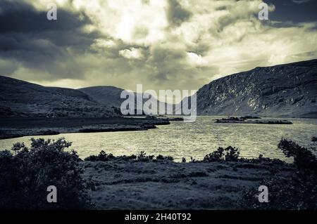 Gespaltene, getönte, stilisierte Darstellung des Glenveagh National Park, County Donegal, Irland, mit sich im Sommer aufziehenden Sturmwolken Stockfoto