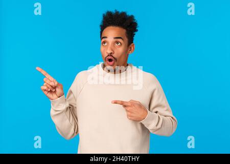Sprachlos und beeindruckt, erschreckt attraktiven afroamerikanischen Freund sehen, was er braucht, verlieren Rede stehend blau b Stockfoto