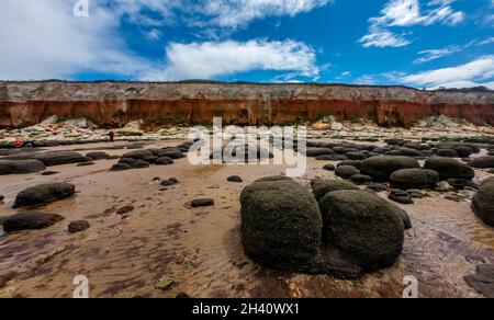 Weitwinkelansicht des Old Hunstanton Beach mit Felsen und orange gestreiften Klippen und blauem Himmel mit Wolken im oberen Drittel Stockfoto