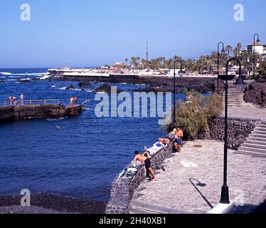 Schwimmer Tauchen vor einem kleinen Hafenmauer mit Lido Martianez nach hinten, Puerto De La Cruz, Teneriffa, Kanarische Inseln, Spanien. Stockfoto