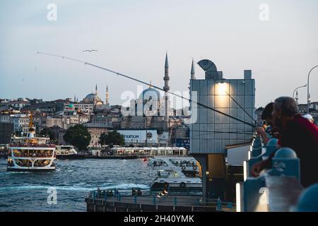 ISTANBUL, TÜRKEI - 10. AUGUST 2021: Auf der Galata-Koprusu-Brücke über das Goldene Horn treffen sich Einheimische, um bei Sonnenuntergang zu fischen und Kontakte zu knüpfen Stockfoto