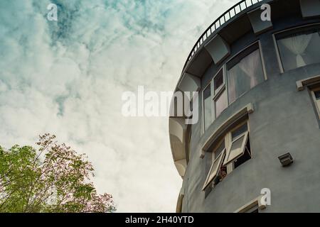 Bottom-up-Ansicht Beton grau modernen Himmel Turm Gebäude mittelalterliche Festung Burg Stil Rundes Dach ragen Backstein Metall Geländer großes Fenster. Ungewöhnlich Stockfoto