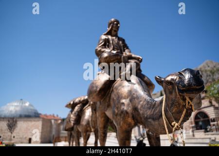 TOKAT, TÜRKEI - 6. AUGUST 2021: Gruppe von Bronzestatuen, die eine Karawane mit Männern und Kamelen vor dem historischen Museum von Tokat darstellen Stockfoto