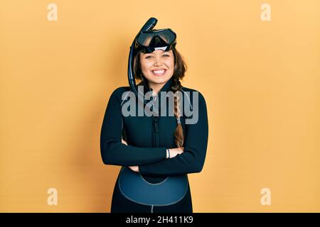 Junge hispanische Mädchen trägt Taucher Neopren Uniform glückliches Gesicht lächelnd mit gekreuzten Armen Blick auf die Kamera. Positive Person. Stockfoto