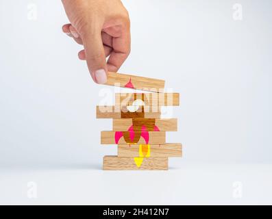 Startup-Konzept für Unternehmen. Hand setzen das letzte Stück Holzblock auf die Oberseite des Holzstapels, um das Puzzle auf die komplette Rakete sym zu ordnen Stockfoto
