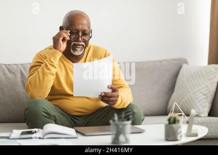 Senior African Male Working With Papers Wearing Eyelasses Sitting Indoor Stockfoto
