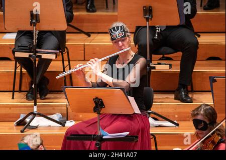 Hamburg, Deutschland. Oktober 2021. Eine Musikerin des Hamburger Symphonieorchesters trägt eine Halloween-Maske und spielt ihre Flöte im großen Saal der Laeiszhalle. Für das Halloween-Konzert zum Auftakt der Kinderkonzertsaison wurden junge und alte Gäste eingeladen, sich in die Laeiszhalle zu kleiden. Es war das erste Kinderkonzert nach einer langen Pause. Quelle: Jonas Walzberg/dpa/Alamy Live News Stockfoto