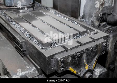 Nahaufnahme eines Teils der horizontalen Fräsmaschinen und Werkzeuge mit Eisenabfällen nach der Metallbearbeitung in der Werkstatt der Industrieanlage. Stockfoto