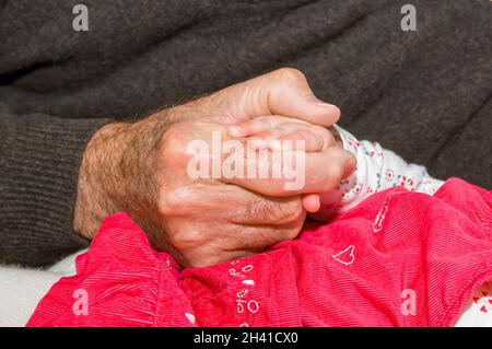 Horizontale Nahaufnahme eines stolzen Großvaters, der die Hand seiner Enkelin hält. Stockfoto