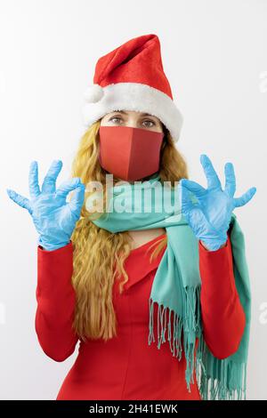 Lady santa zeigt in einer Schutzmaske türkisfarbenen Schal und blauen medizinischen Handschuhen ok Geste Stockfoto