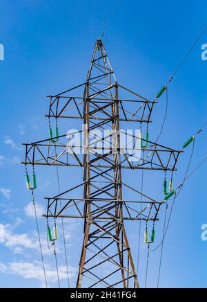 Elektrischer Turm mit transparenten türkisfarbenen Hochspannungsisolatoren oder Isolator in Sonnenlicht auf elektrischem Turm auf blauem Himmel Hintergrund. Elektrische Leistung tra Stockfoto