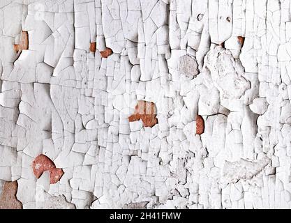 Alte, rissige weiße Farbe blättert von der Wandstruktur ab. Nahaufnahme von gerissenen Farben. Stockfoto