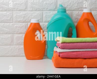 Plastikflaschen mit Flüssigwaschmittel und gefalteten Handtüchern auf einem weißen Regal. Inneneinrichtung des Badezimmers Stockfoto
