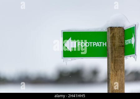 Öffentliches Wanderwegschild nach links mit Schnee und Eiszapfen auf dem ländlichen britischen Land Stockfoto