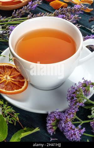 Kräutertee. Kräuter, Blumen und Früchte um eine Tasse Tee auf einem Holzhintergrund Stockfoto