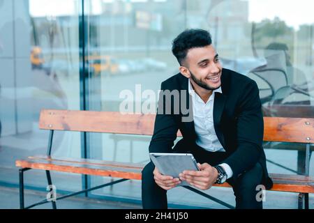 Mann in Anzug arabisch setzt auf Sonnenbrille mit Tablet in der Nähe von Business Center Stockfoto
