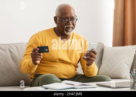 Senior African Male Shopping Mit Kreditkarte Und Smartphone Indoor Stockfoto