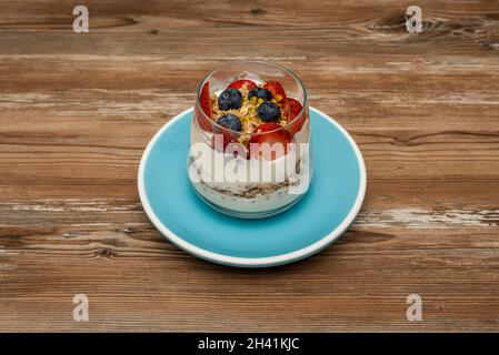 Müsli ist ein Lebensmittel, das aus Nüssen, Haferflocken, gemischt mit Honig und anderen natürlichen Zutaten mit Heidelbeeren, Erdbeeren und Joghurt besteht Stockfoto