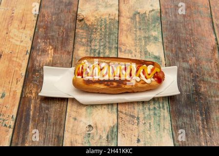 Köstlicher traditioneller Hot Dog mit gekochter Wurst, Senf, Ketchup und Mayonnaise auf dem Holztisch Stockfoto