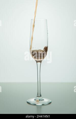 Eine Erdbeere fiel in ein Glas Wasser.Getränke mit aufgespritzten Früchten auf Weiß Stockfoto