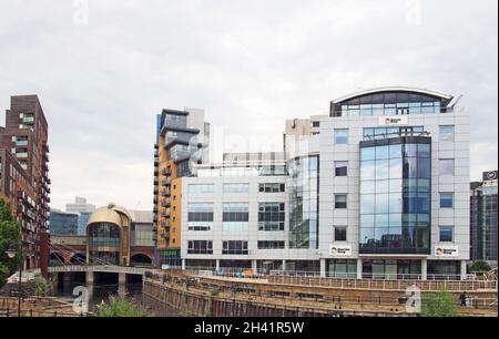 Blick auf leeds mit dem Fluss aire in die dunklen Bögen unter dem Bahnhof mit Fußgängerbrücke und Büro und ein Stockfoto