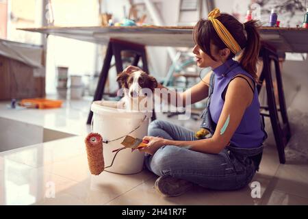 Junge Künstlerin und ihr Hund bei der Werkstatt .Kreativ inspirierte Stimmung. Stockfoto