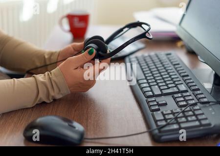 Kaukasische Frau Hände halten Mikrofon-Headset. Call Center, Büro, Remote oder Work from Home Konzept. Stockfoto