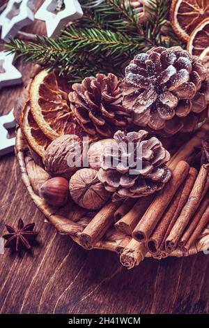 Getrocknete Orange, Sternanise, Zimt, Tannenzapfen und Tannenbaum in rustikalem Teller auf Holztisch. Hausgemachte Medley-Idee für Weihnachtsstimmung und Aroma. Öko-Frie Stockfoto