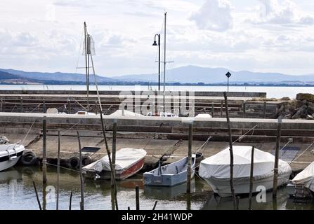Kleine Motorboote, die auf hölzernen Pfählen eines kleinen Hafens im Trasimenischen See (Umbrien, Italien, Europa) festgemacht sind Stockfoto