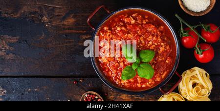 Traditionelle italienische Bolognese-Sauce in Saucepot auf einem alten dunklen Holzhintergrund. Draufsicht, Kopierbereich Stockfoto