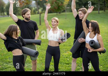 Menschen mit Fitnessmatten stehen auf einer grünen Wiese Stockfoto