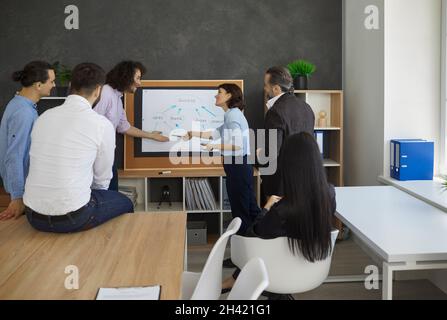 Gruppe von Mitarbeitern, die Kollegen zuhören, die sich während des Arbeitsmeeting in Streit verwickelt haben Stockfoto