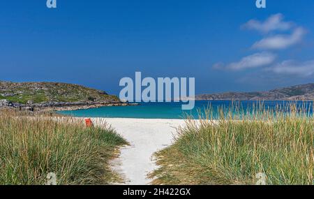 ACHMELVICH LOCHINVER SUTHERLAND SCHOTTLAND EIN BLAUER HIMMEL TÜRKISFARBENES MEER WEISSER SANDSTRAND UND EIN ROTER STUHL Stockfoto