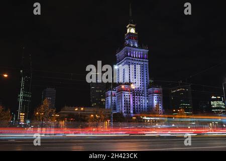 Palast der Kultur und Wissenschaft, beleuchtet bei Nacht im Stadtzentrum von Warschau. Ampel und Fahrzeuge in Bewegung bei Langzeitbelichtung. Warschau, Polen - 23. Oktober 2021 Stockfoto