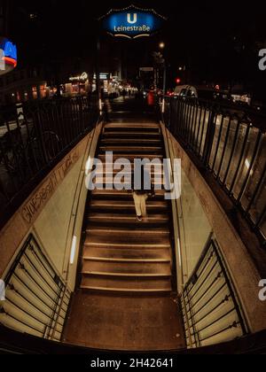 Oktober 2021 - Berlin Deutschland. Frau steigt nachts von der U-Bahnstation Leinestraße die Treppe hoch. Stockfoto