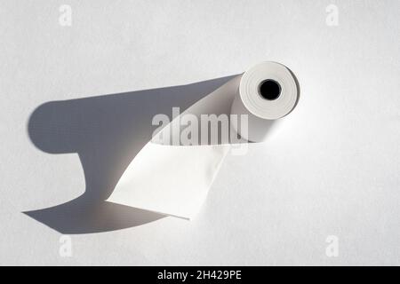 Rolle Kassettenpapierband mit Schatten auf weißem Papier, Platz für Kopien. Rolle Kassettenband, Papierrolle mit Kassenbeleg, isoliert auf weißem Hintergrund Stockfoto