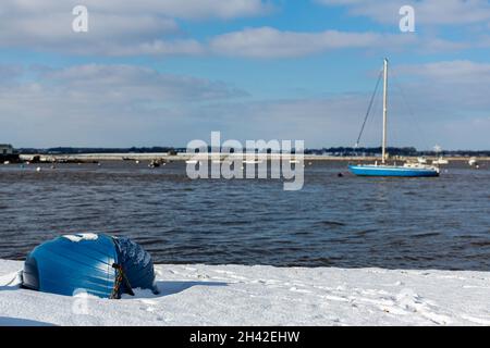 Umgedrehte Ruderboote wurden am Strand an der Küste von Suffolk vertäut. Sie wurden mit Schnee bedeckt, nachdem ein seltener Schneesturm das Gebiet bedeckt hatte Stockfoto