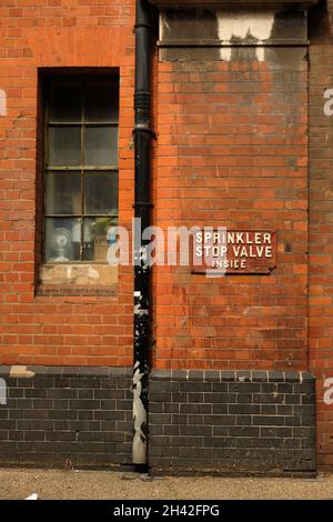August 2021 - Fenster und Schild für einen Sprinklerabsperrschieber in einem alten Industrielager im Zentrum von London, England. Stockfoto