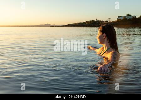 Eine junge schottische Frau, die im Oktober bei Sonnenaufgang im Meer bei Aberdour in Fife, Schottland, schwimmt Stockfoto