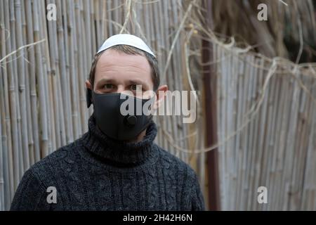 Nahaufnahme Porträt eines gut aussehenden erwachsenen jüdischen Mannes, der Kippah auf Hebräisch oder Yarmulke trägt (Stoffkappe, die traditionell von jüdischen Männern getragen wird) mit Maske auf der Str. Stockfoto