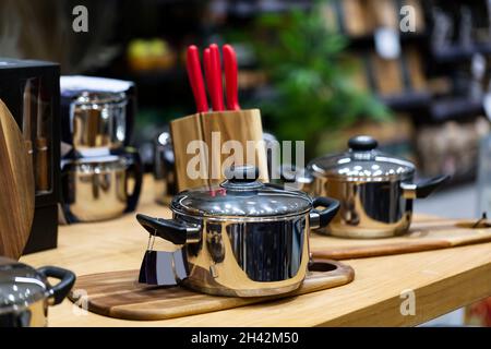 geschirr, Kochgeschirr auf Holztisch. Wunderschöne, moderne, neue Pfannen. Interieur und Design der modernen Wohnküche. Unscharfer Hintergrund, selektiver Fokus Stockfoto