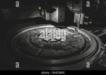 Späne nach der Verarbeitung der gusseisernen Luke auf der Karussellmaschine in der Werkstatt des Industriewerks. Stockfoto