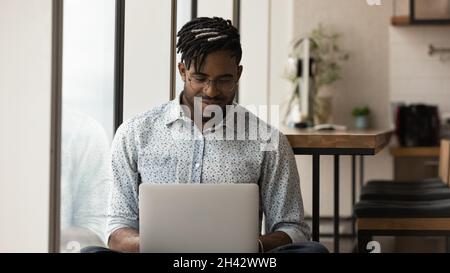 Glücklicher junger afroamerikanischer Freiberufler, der am Computer arbeitet. Stockfoto