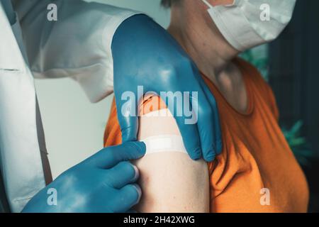 Arzt, der nach dem Covid-19-Impfverfahren Gips auf die weibliche Schulter aufsetzt, Impfkonzept Stockfoto