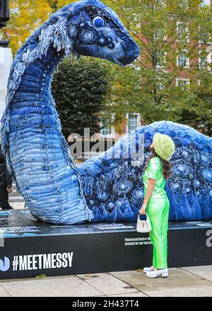 Grosvenor Square, London, Großbritannien. Oktober 2021. Die Leute schauen und posieren mit chaotisch das COP NESS Monster. „Unsy“ besteht vollständig aus recycelten Jeans und anderen nachhaltigen Materialien und wird bis zum 12. November auf dem Grosvenor Square sein. Die Skulptur ist eine Zusammenarbeit zwischen der Künstlerin Billie Achilleos, der Streaming-Plattform WaterBear und DER KREISFÖRMIGEN Denim-Marke MUD Jeans. Kredit: Imageplotter/Alamy Live Nachrichten Stockfoto