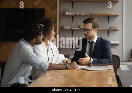 Interessierte junge verschiedene Kunden treffen makler im Büro. Stockfoto