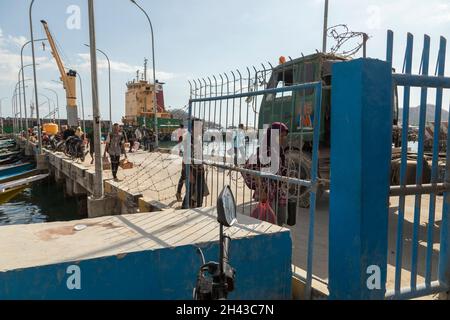 Labuan Bajo, Indonesien - 25. August 2019: Eine Frau und mehrere andere Personen, die vor kurzem mit dem Boot angekommen sind, gehen in Richtung des Ausgangs des Hafens von Labuan Bajo Stockfoto