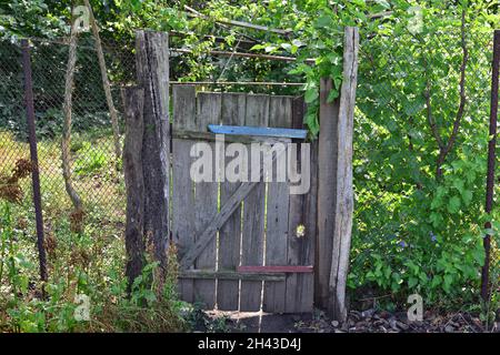 Altes zerbrochenes Holztor im Garten, verwüstete Landschaft. Stockfoto