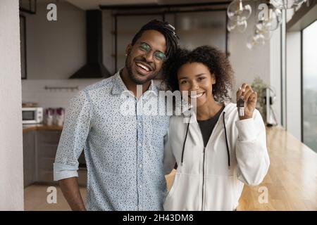 Glückliches junges afroamerikanisches Familienpaar, das Schlüssel zeigt. Stockfoto