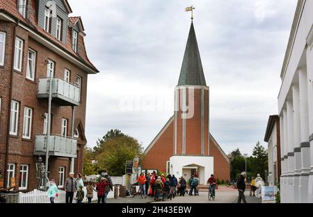 Juist, Deutschland. Oktober 2021. Auf der ostfriesischen Insel Juist laufen die Menschen vor der Inselkirche. Die autofreie Insel Juist gehört zu den ostfriesischen Inseln im niedersächsischen Wattenmeer der Nordsee und liegt zwischen Borkum im Westen und Norderney im Osten. Die Insel hat eine Länge von 17 Kilometern und ist damit die längste der ostfriesischen Inseln. Quelle: Waltraud Grubitzsch/dpa-Zentralbild/dpa/Alamy Live News Stockfoto